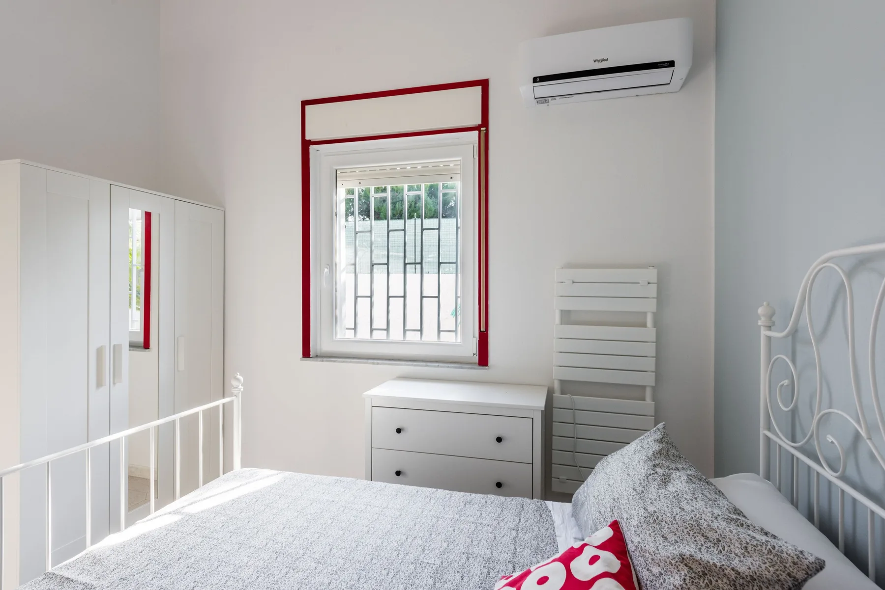 Un dormitorio luminoso con cama, armario y ventana.