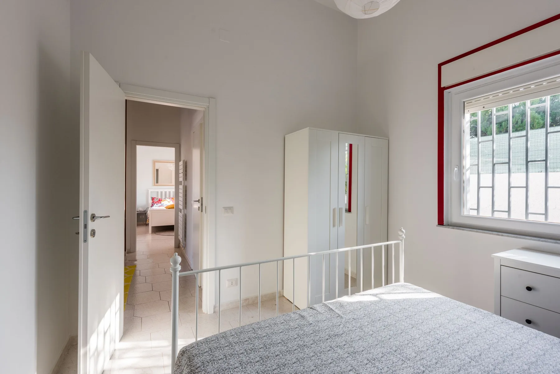 Un dormitorio luminoso con cama, armario y ventana.