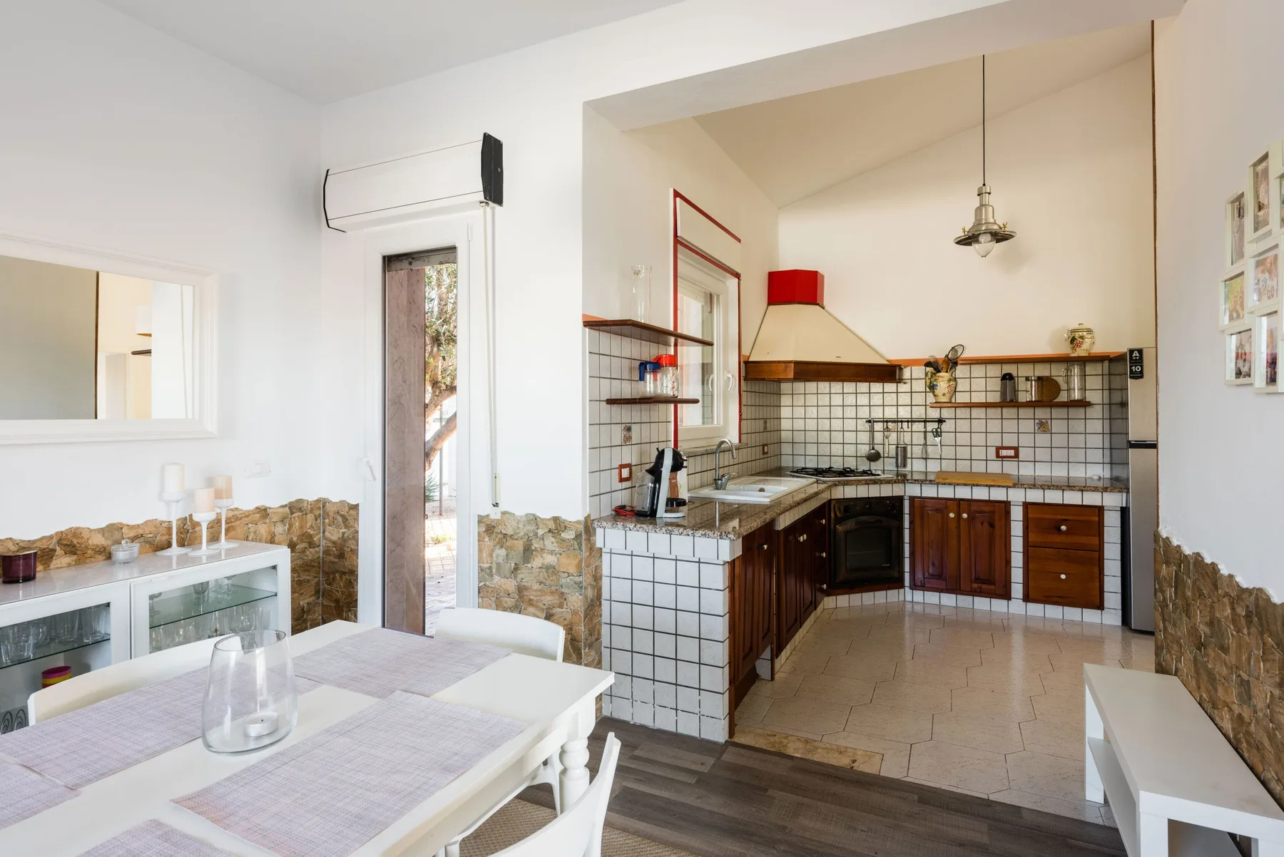 Un comedor se abre a una cocina alicatada con armarios oscuros y una encimera larga.
