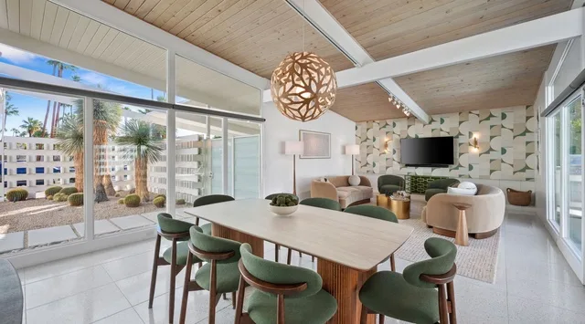 Una luminosa sala de estar y comedor de planta abierta con grandes ventanas y una mesa de comedor.