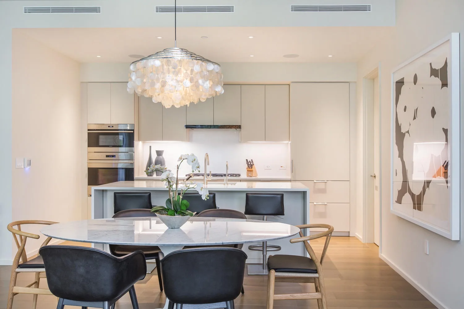 Un comedor moderno con una mesa, asientos y una cocina abierta al fondo.