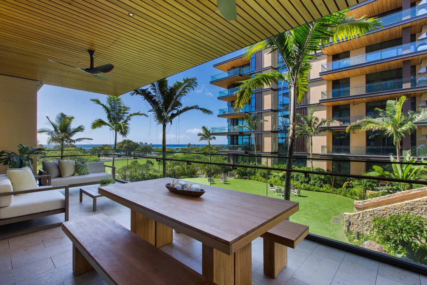Una zona de estar exterior cubierta da a un jardín y a un edificio moderno.