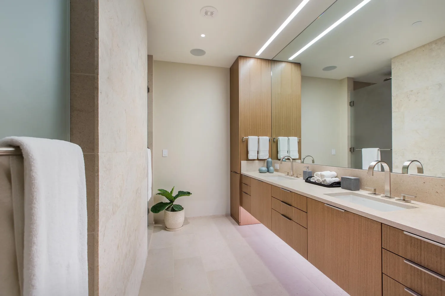 Un baño moderno con un tocador largo, lavabos y un espejo grande.