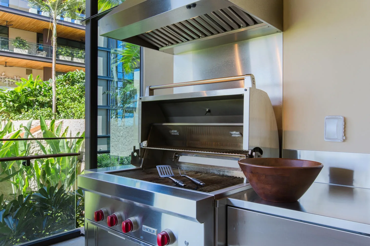 Una zona de parrilla interior con una parrilla de acero junto a grandes ventanales.