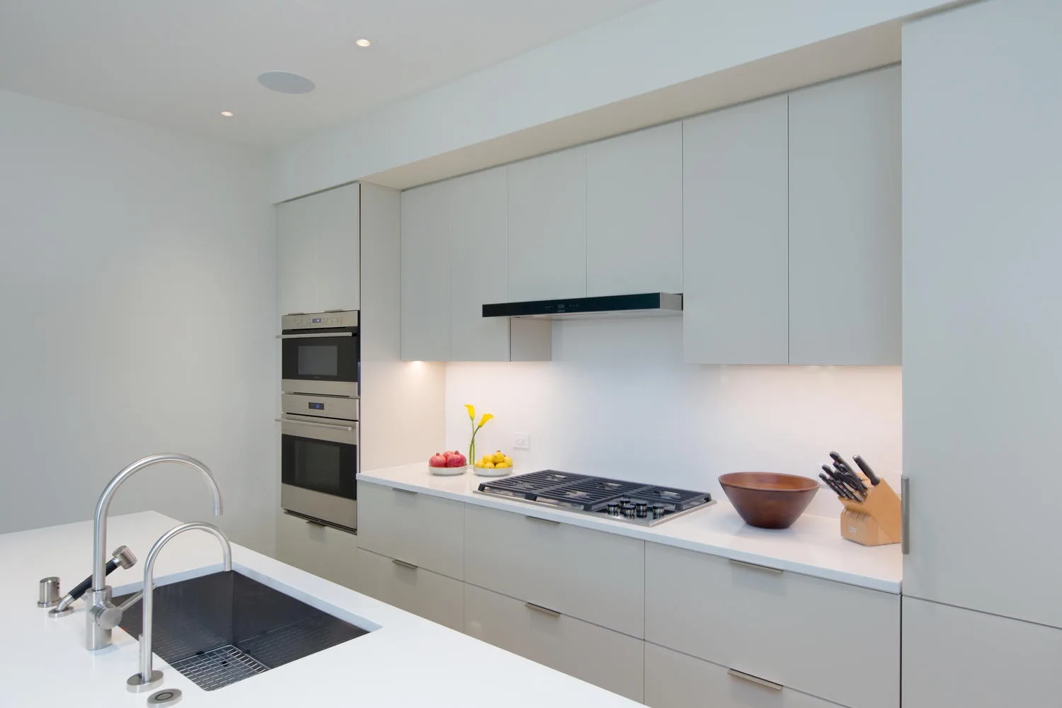Una cocina moderna con armarios blancos, una placa de cocción y un fregadero.