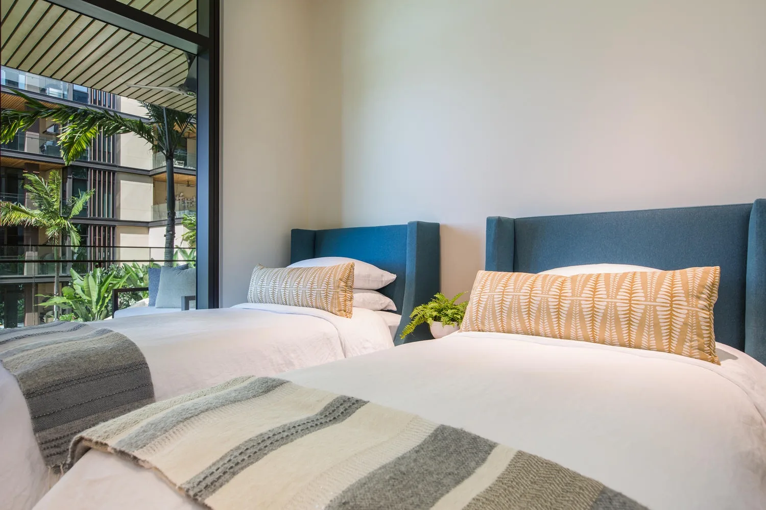 Un dormitorio con dos camas vestidas con ropa blanca junto a una ventana grande.