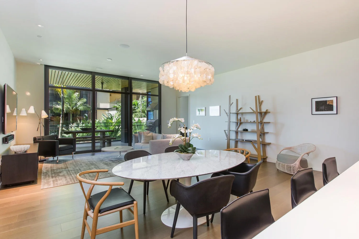 Una luminosa zona de comedor y estar cuenta con una mesa grande y ventanales con vistas a la vegetación.