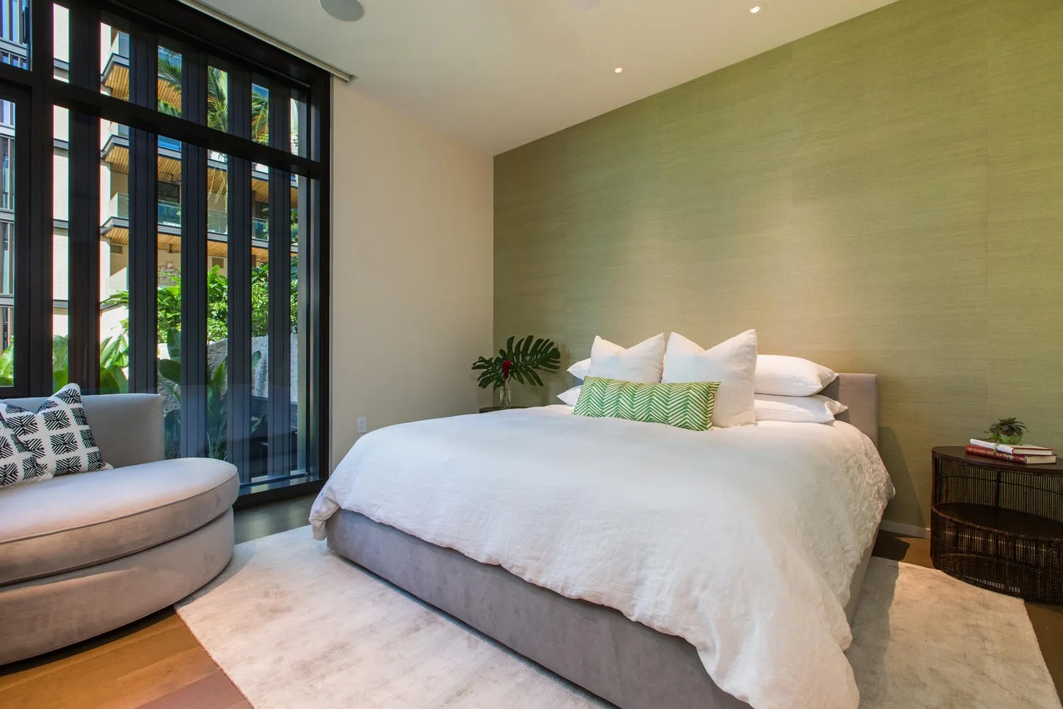 Un dormitorio con una cama grande junto a ventanales y una pequeña zona de estar.