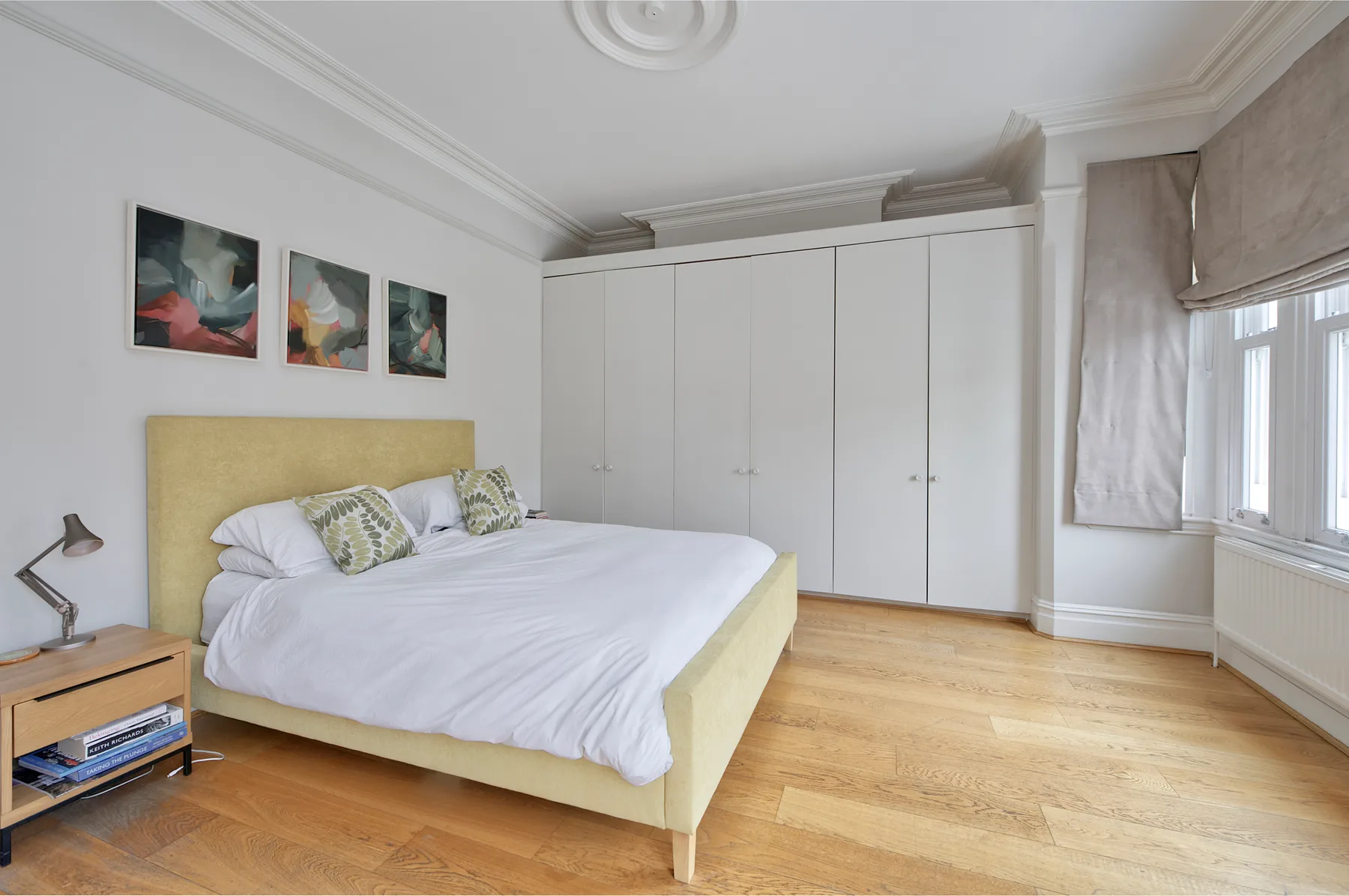 Un dormitorio luminoso con una cama grande, armarios empotrados y una ventana.