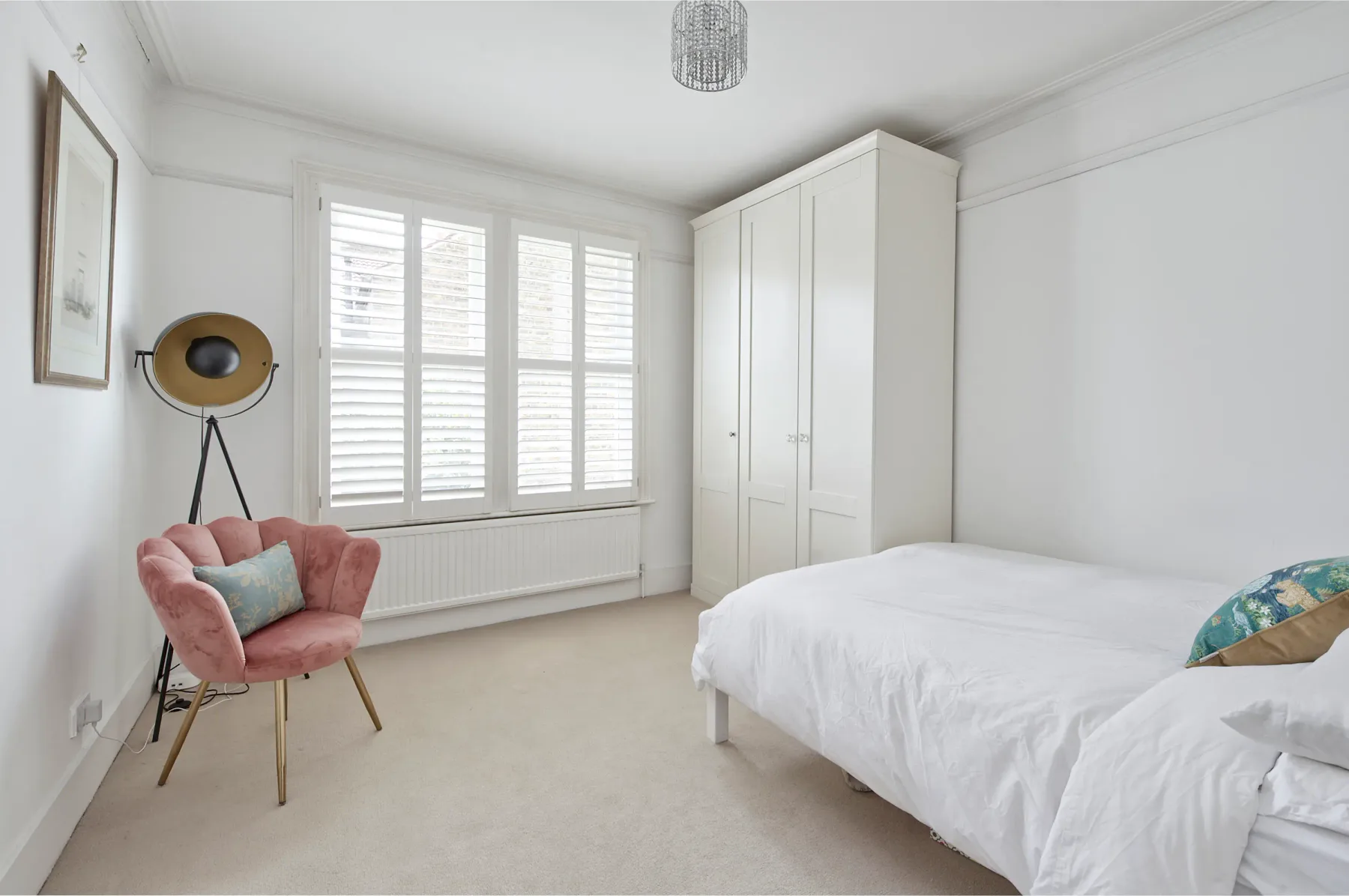 Un dormitorio luminoso con cama, armario y asiento rosa.