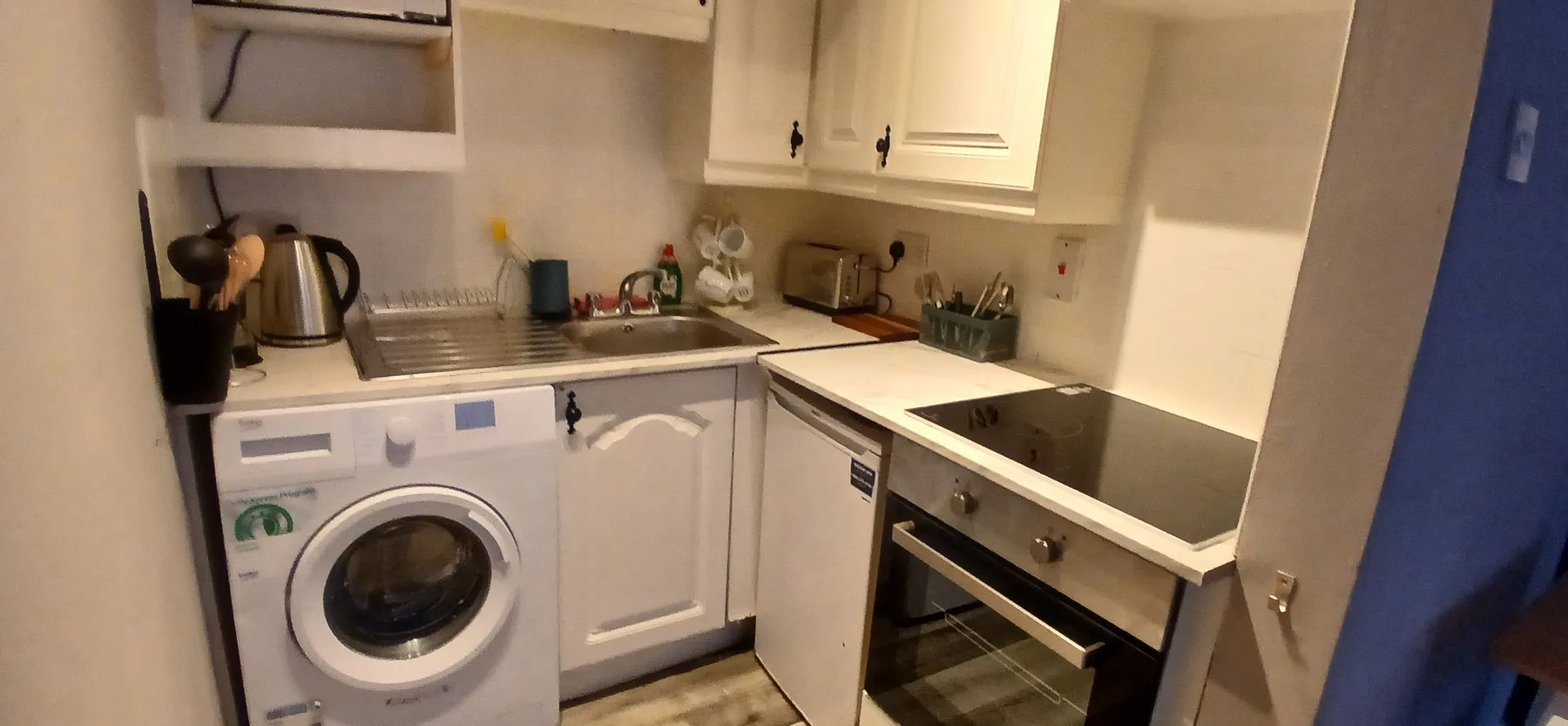 Una cocina compacta con fregadero, encimera y electrodomésticos integrados.