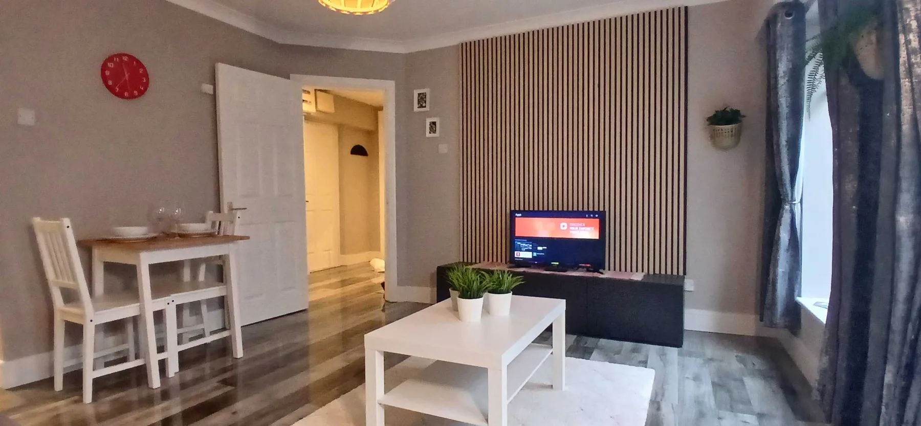Una sala de estar con televisor, mesa de centro y comedor.