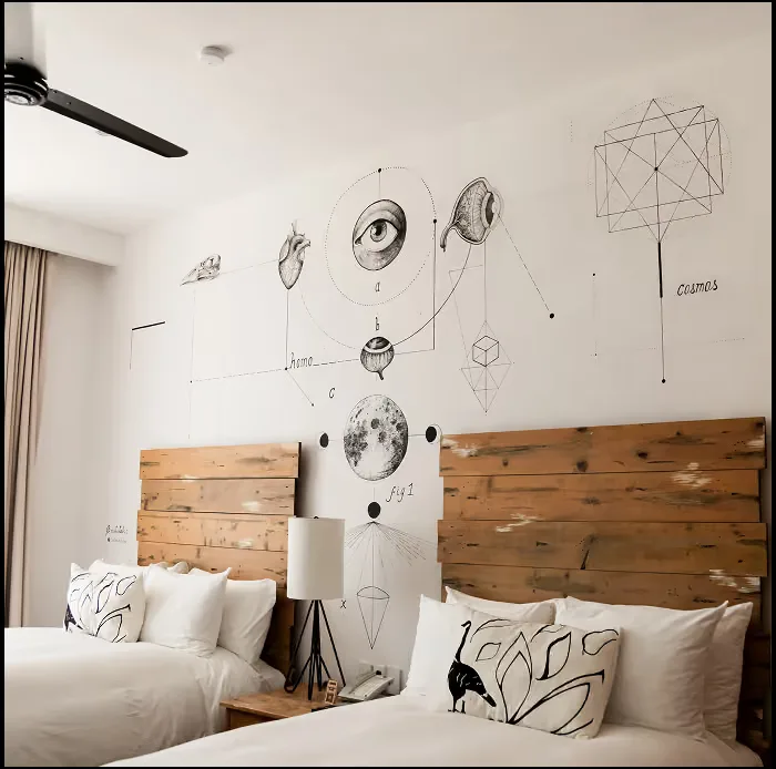 Habitación con dos camas y un mural ilustrado en la pared.