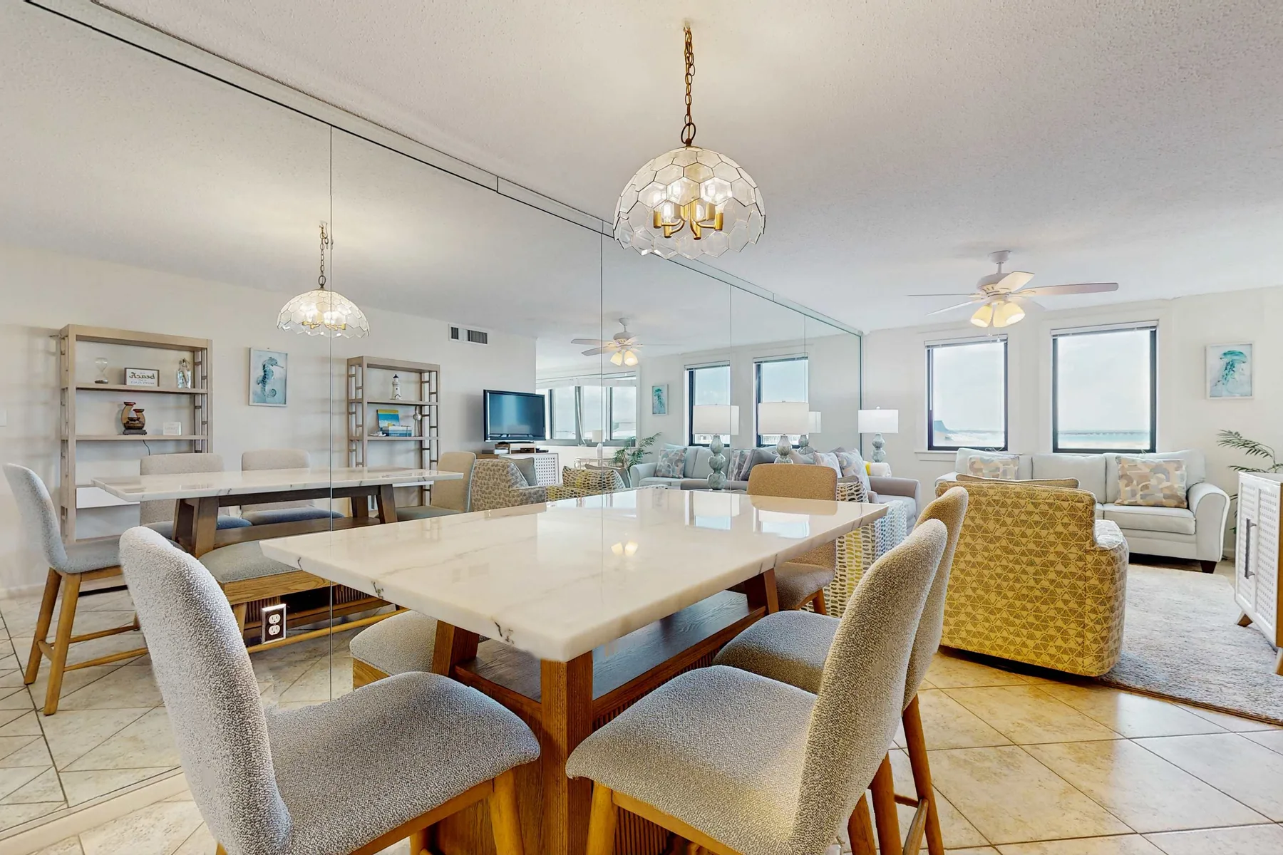 A bright dining and living area with a large table and upholstered seating.