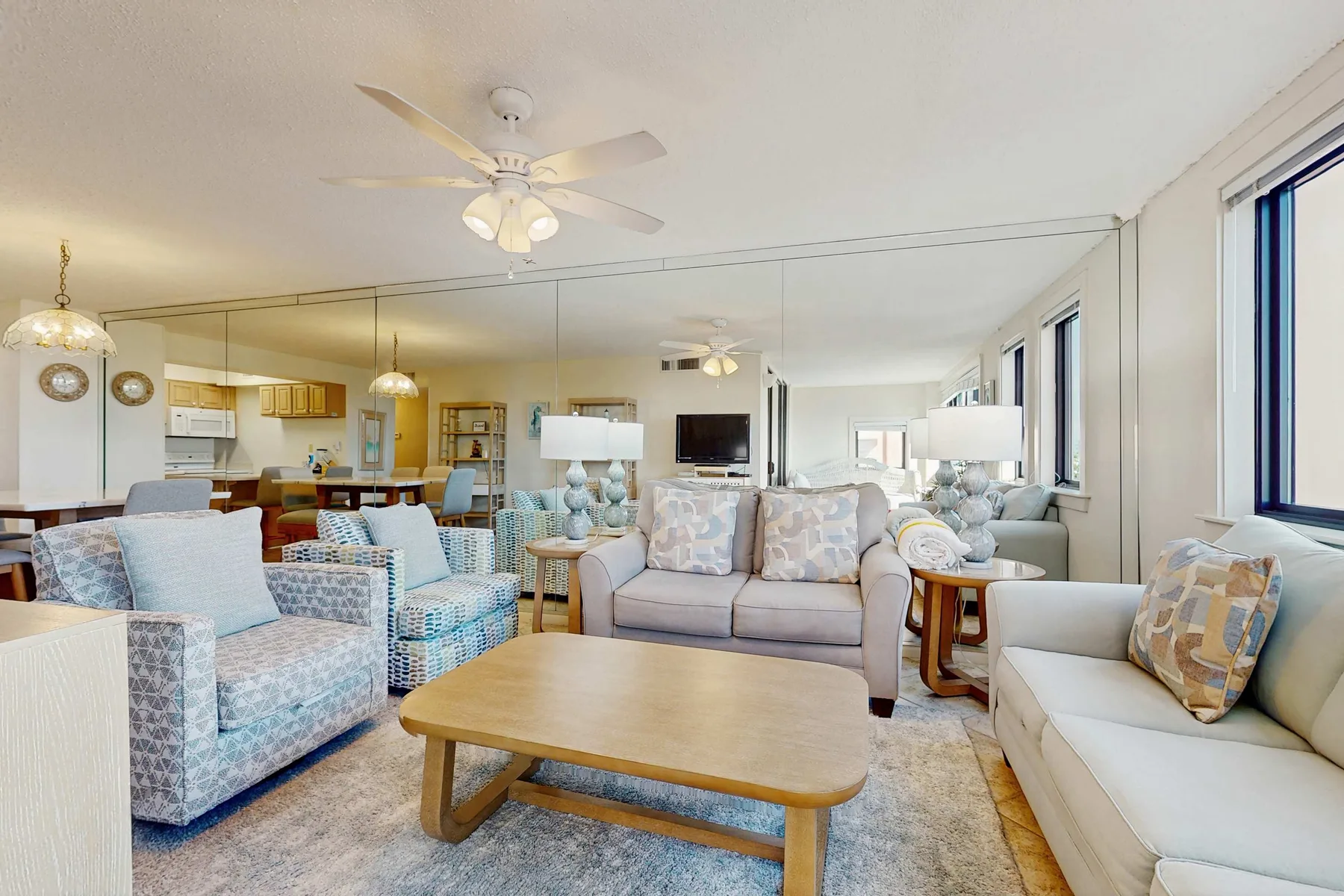 A bright living room with seating around a coffee table and an open kitchen beyond.