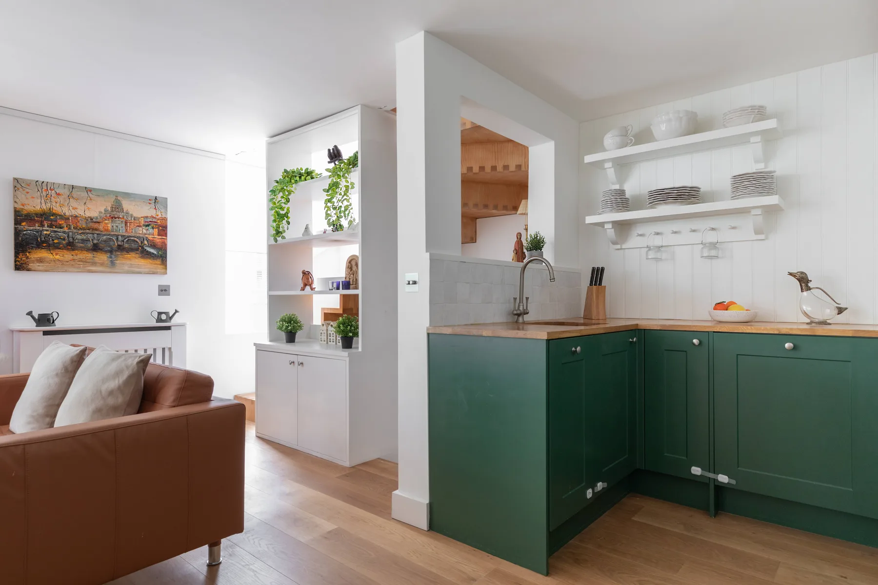 A bright kitchen with green cabinets and an adjoining living area.