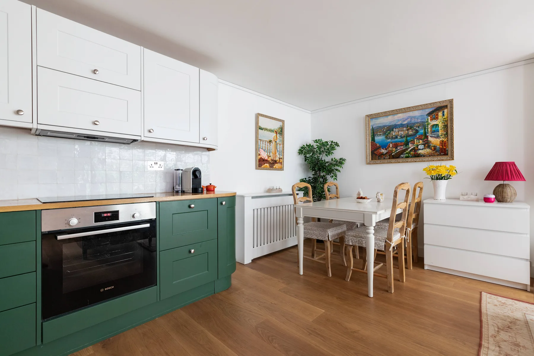A bright kitchen and dining area with green cabinets and a dining table.