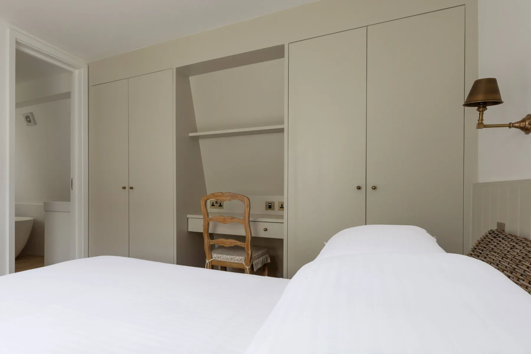A bedroom with a bed and built-in cupboards along the back wall.