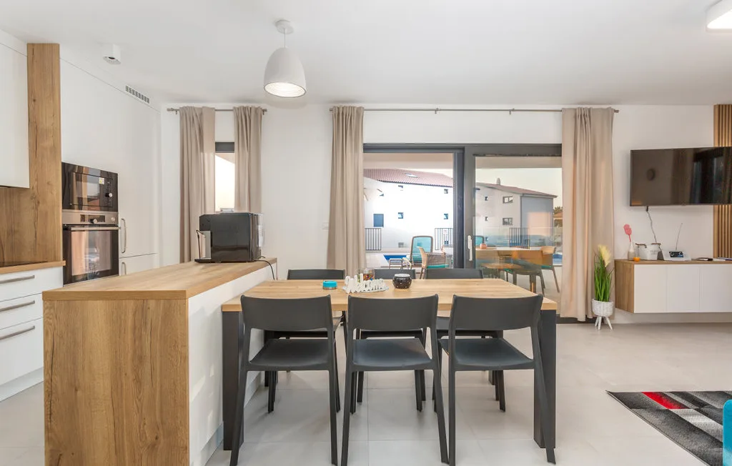 An open-plan kitchen and dining area with a table beside large glass doors.