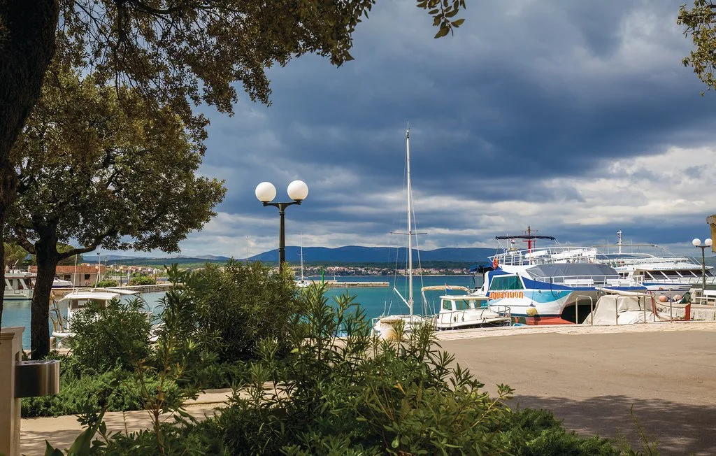 A waterfront harbor with boats moored beside a paved quay.