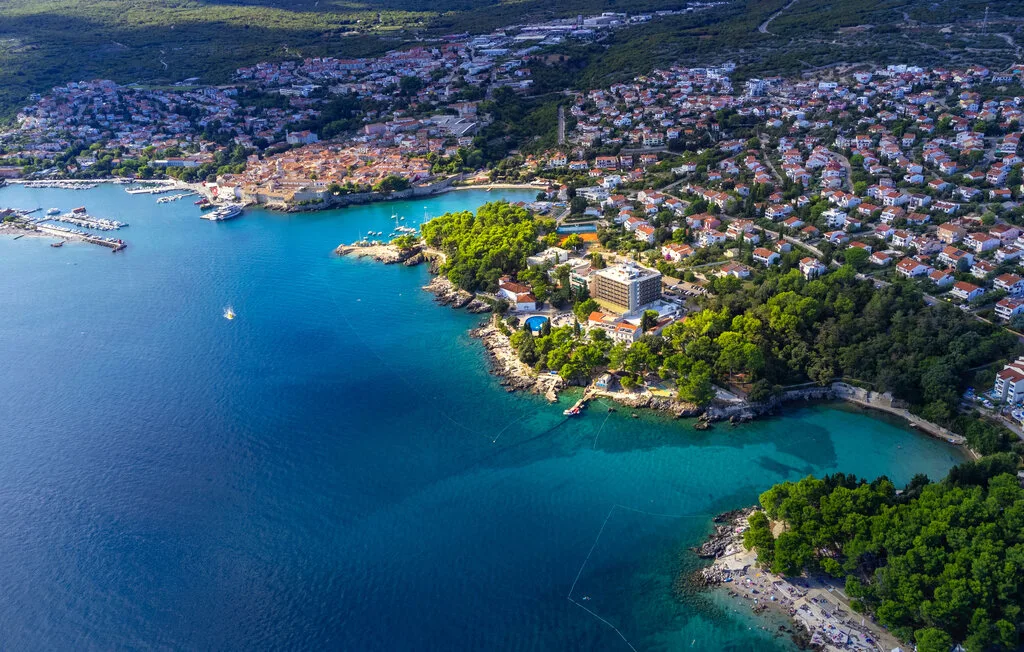 An aerial view of a coastal town beside a sheltered bay and wooded shoreline.