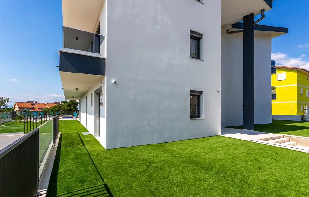 A modern white building borders a green lawn and narrow paved walkway.