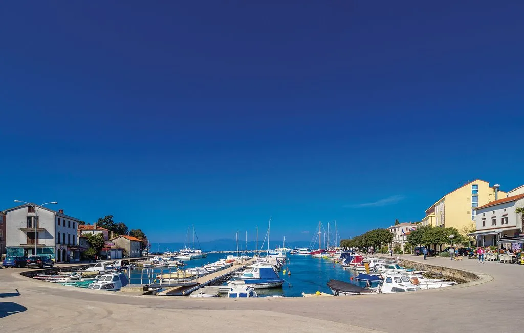 A marina with boats moored along a waterfront lined with buildings.
