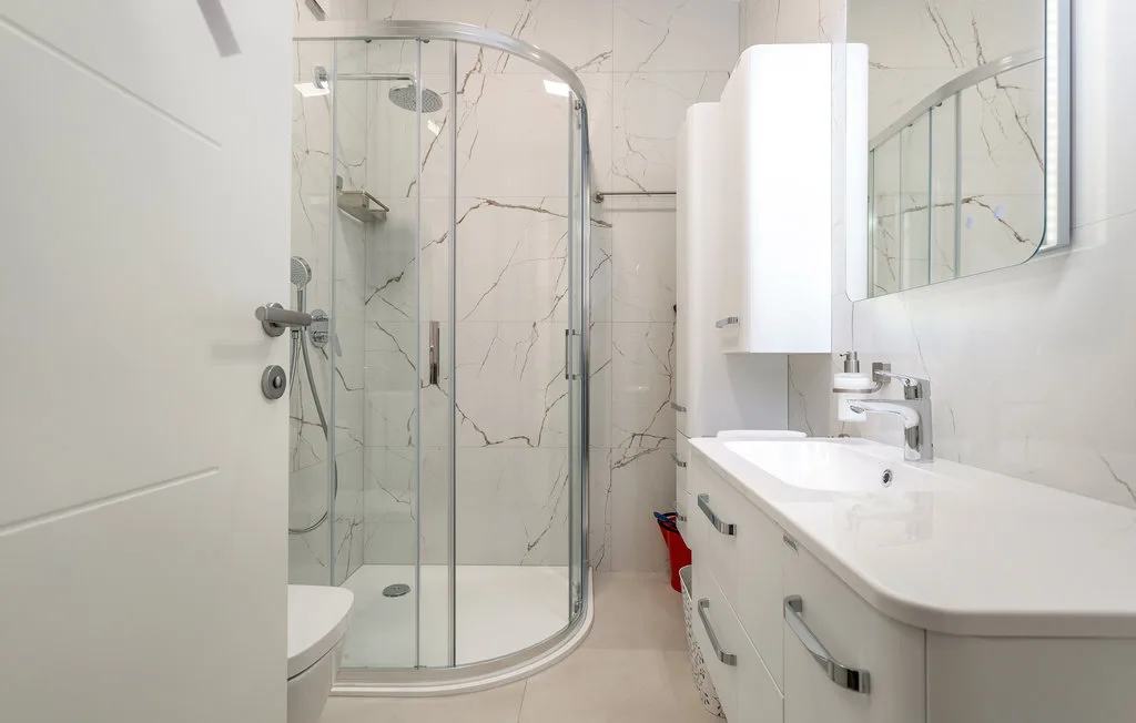 A bright bathroom with a glass shower and a white sink vanity.