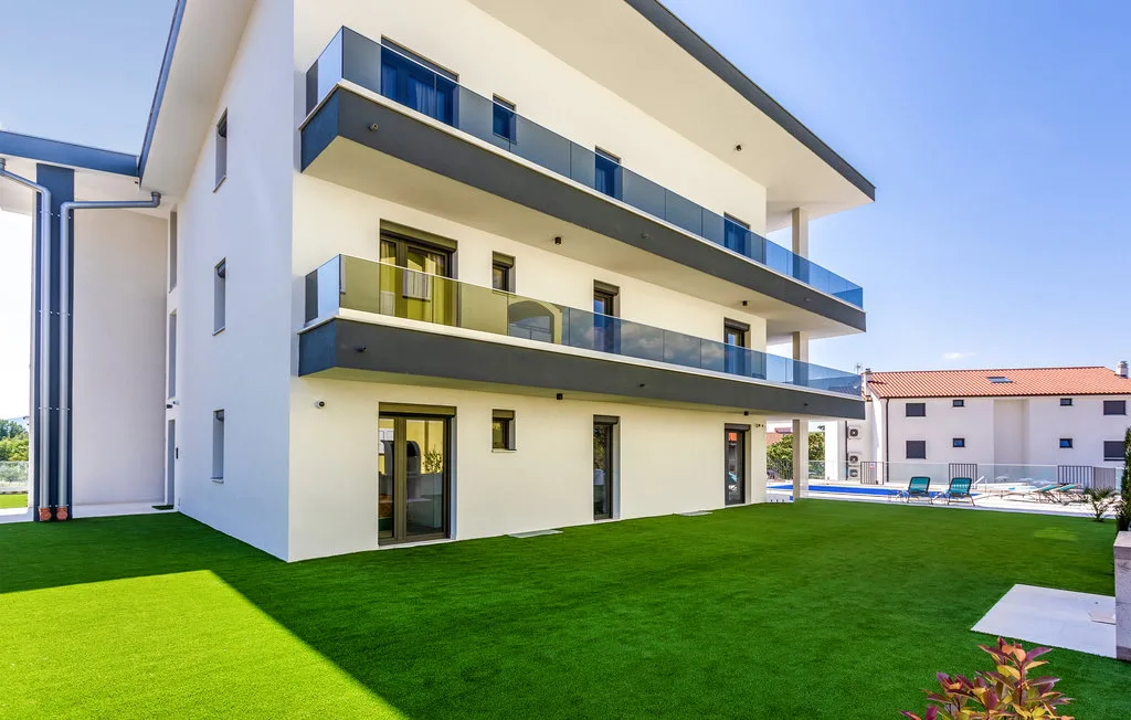 Modern apartment building with balconies overlooking a green lawn.