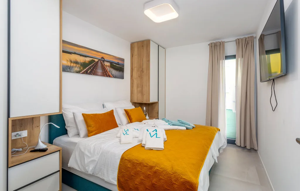 A bright bedroom with white bedding and a mustard-yellow bedspread.