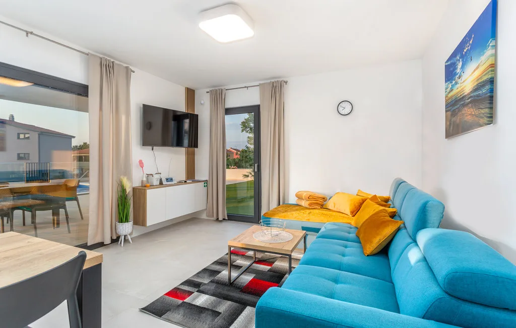 A bright living room with a blue sofa and glass doors opening onto a balcony.