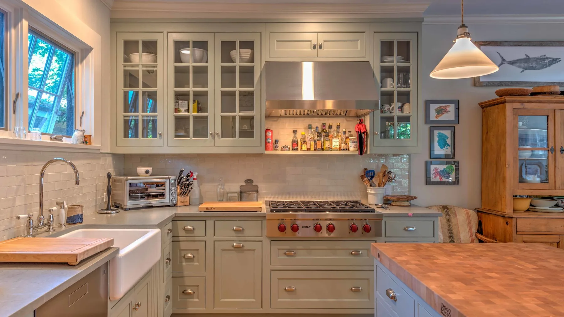 A kitchen with pale cabinets, a central range, and a butcher-block island.