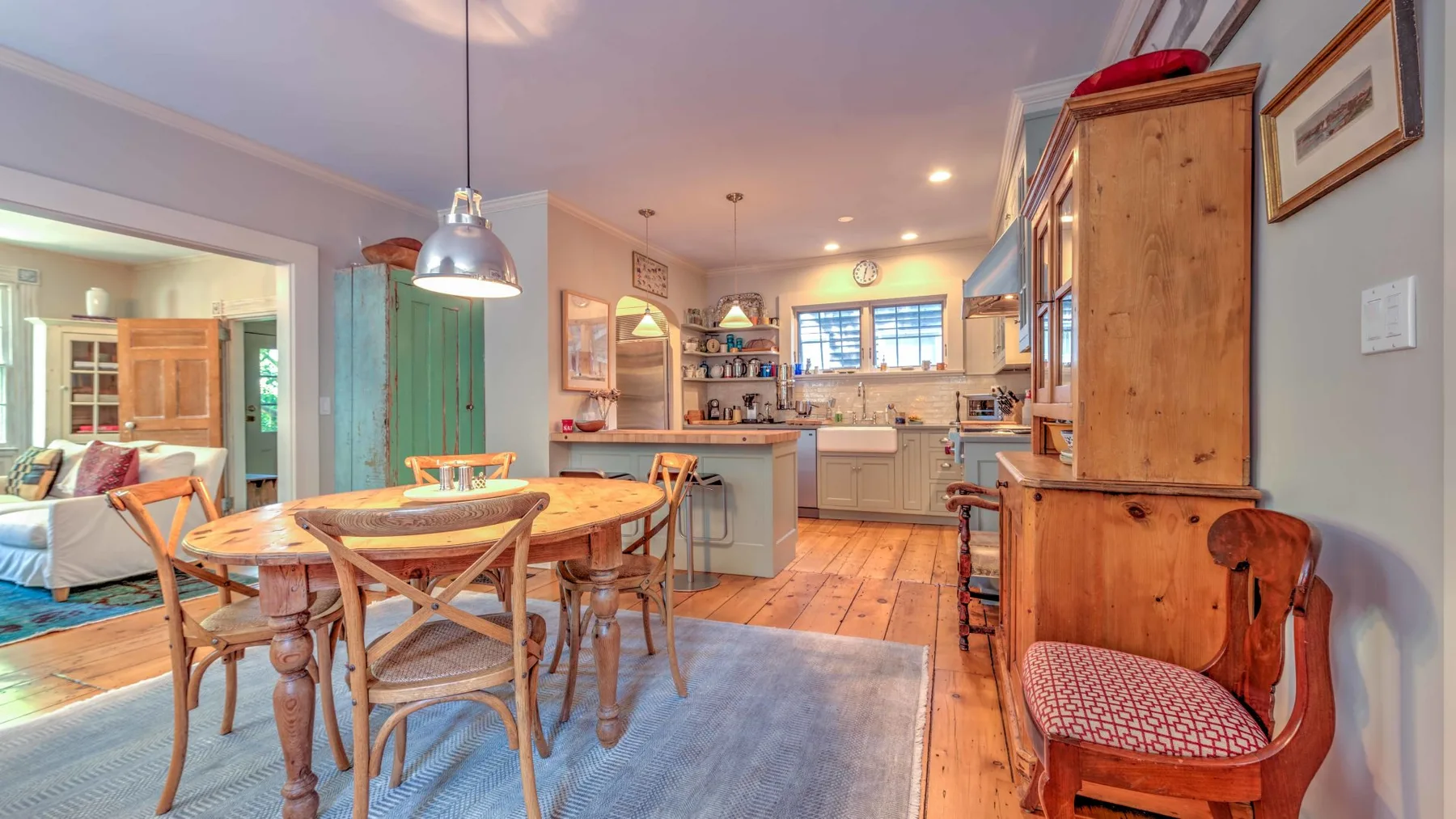 Un comedor con mesa y sillas de madera se abre a una cocina.