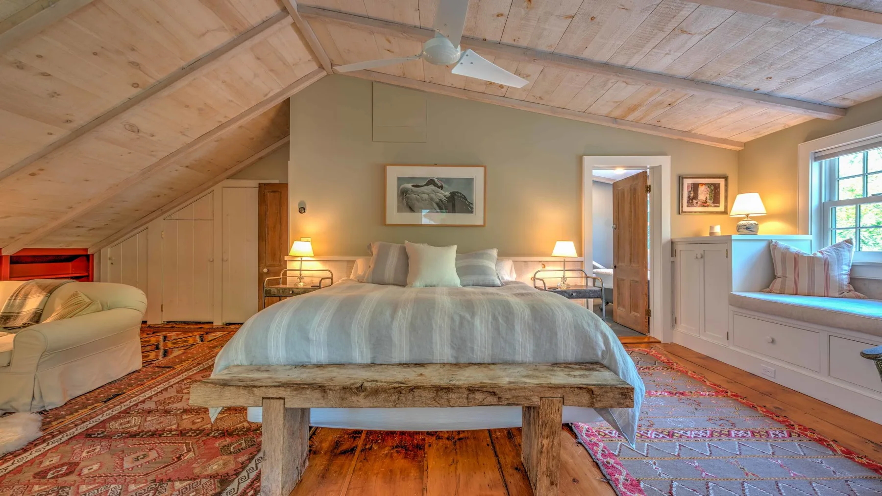 Un dormitorio con una cama grande bajo un techo de madera inclinado.