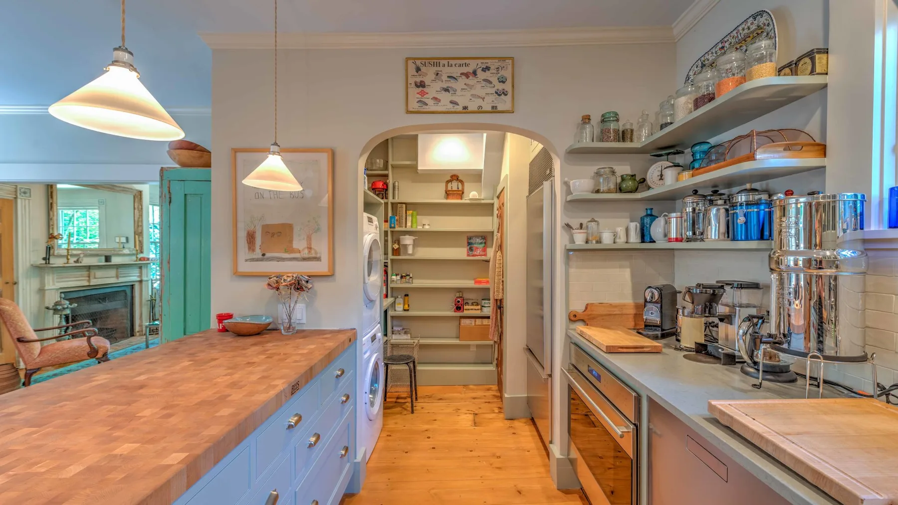 Una cocina luminosa con una isla larga y estantes abiertos con platos y frascos.