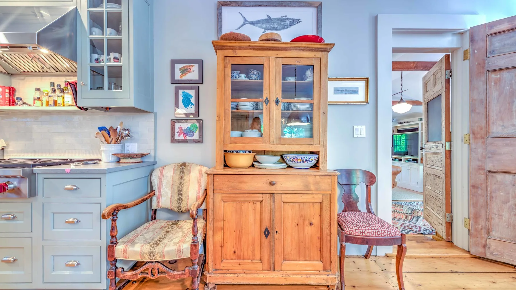 Una cocina y zona de comedor con un mueble de madera y dos sillas tapizadas.