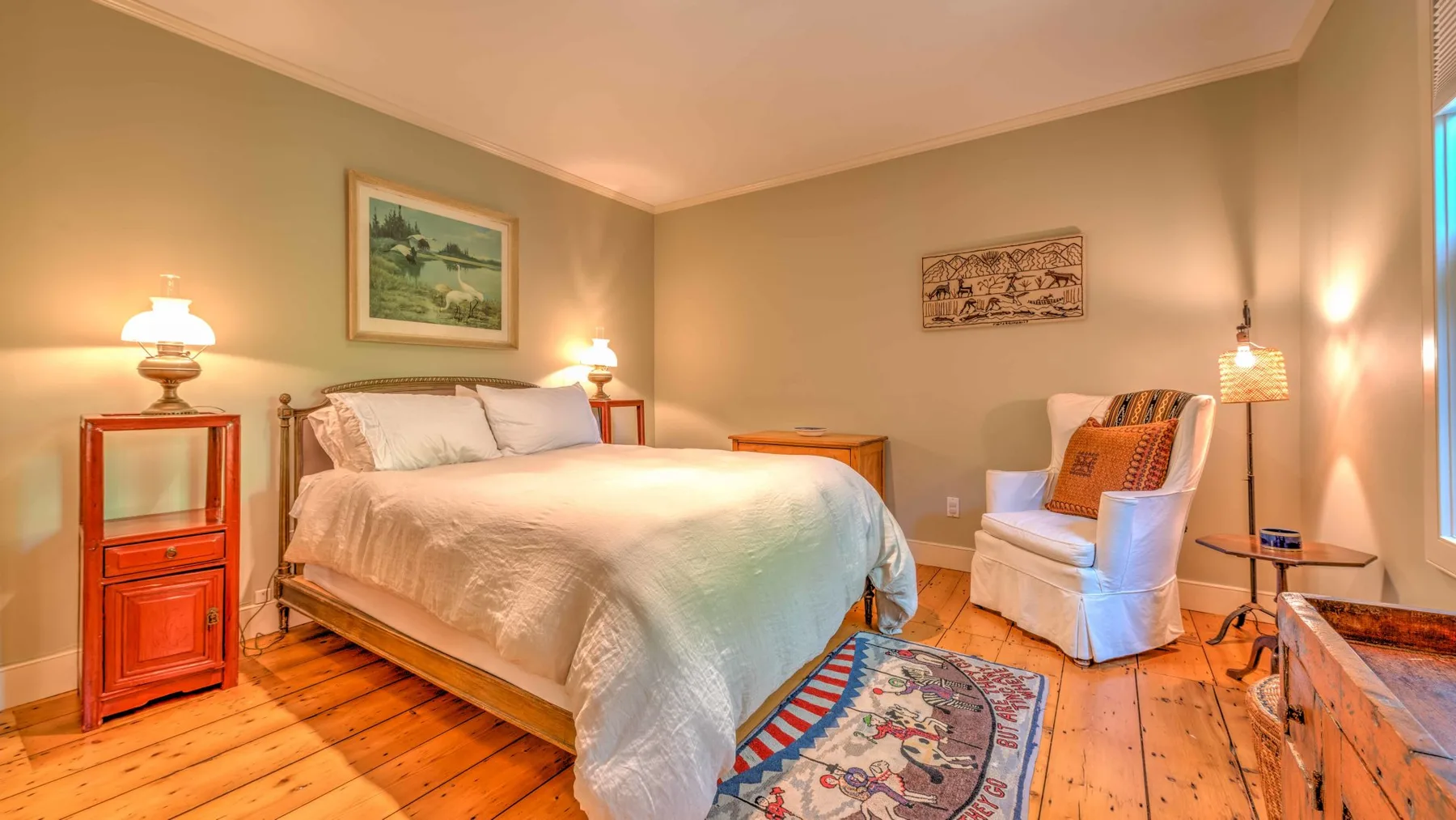 Un dormitorio con una cama, lámparas de noche y una alfombra estampada.
