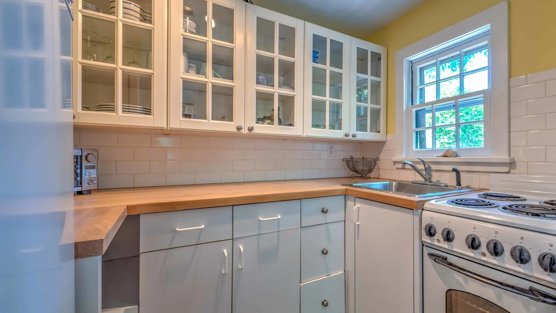 Una cocina luminosa con gabinetes claros, encimeras de madera y una estufa.