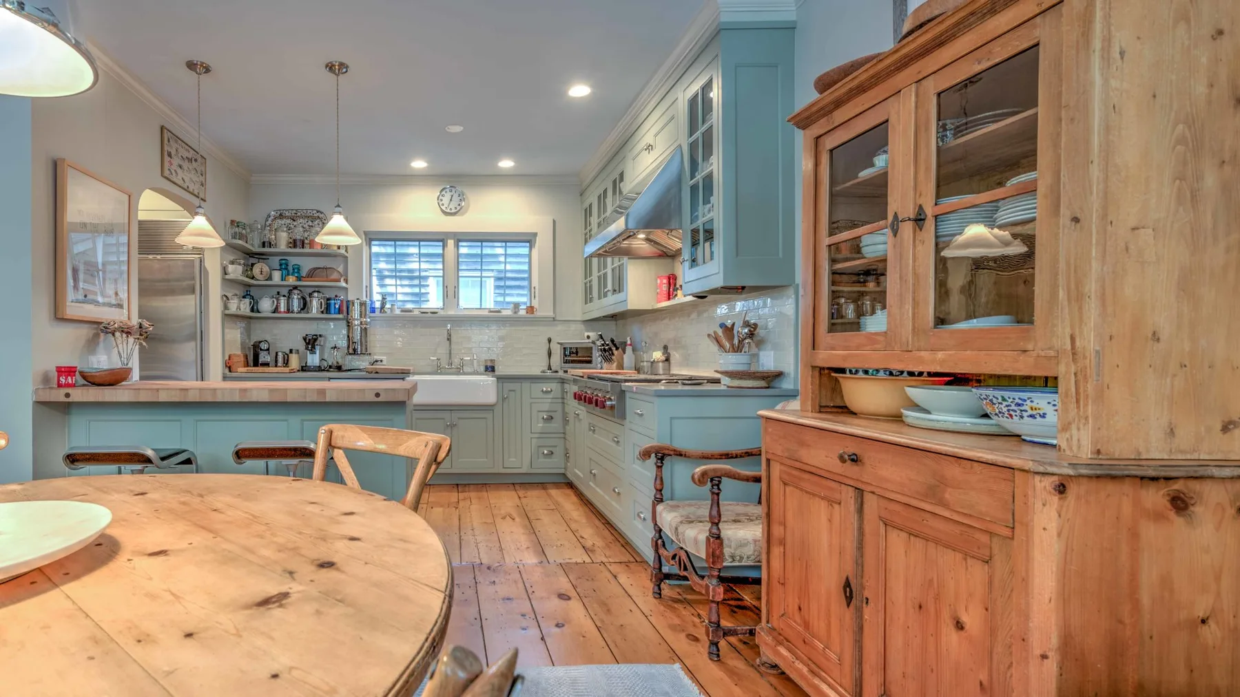 Una cocina con gabinetes azul claro, encimeras de madera y una gran mesa de comedor.