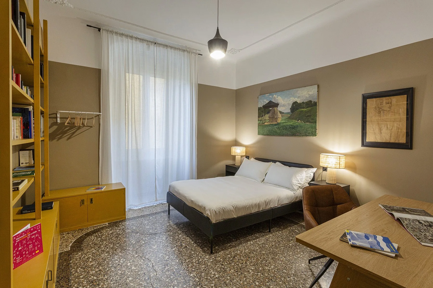 A bedroom with a bed, bedside lamps, and a desk.