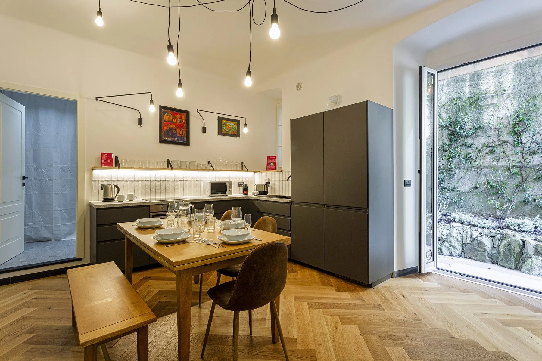 Una cocina y comedor con una mesa de madera bajo luces colgantes.