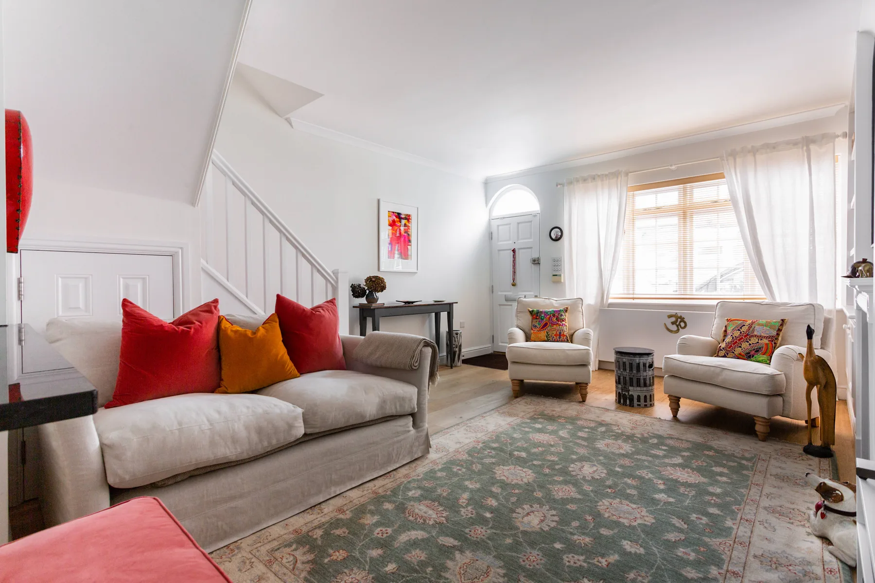 Una sala luminosa con asientos acolchados, cojines de colores y una alfombra estampada.