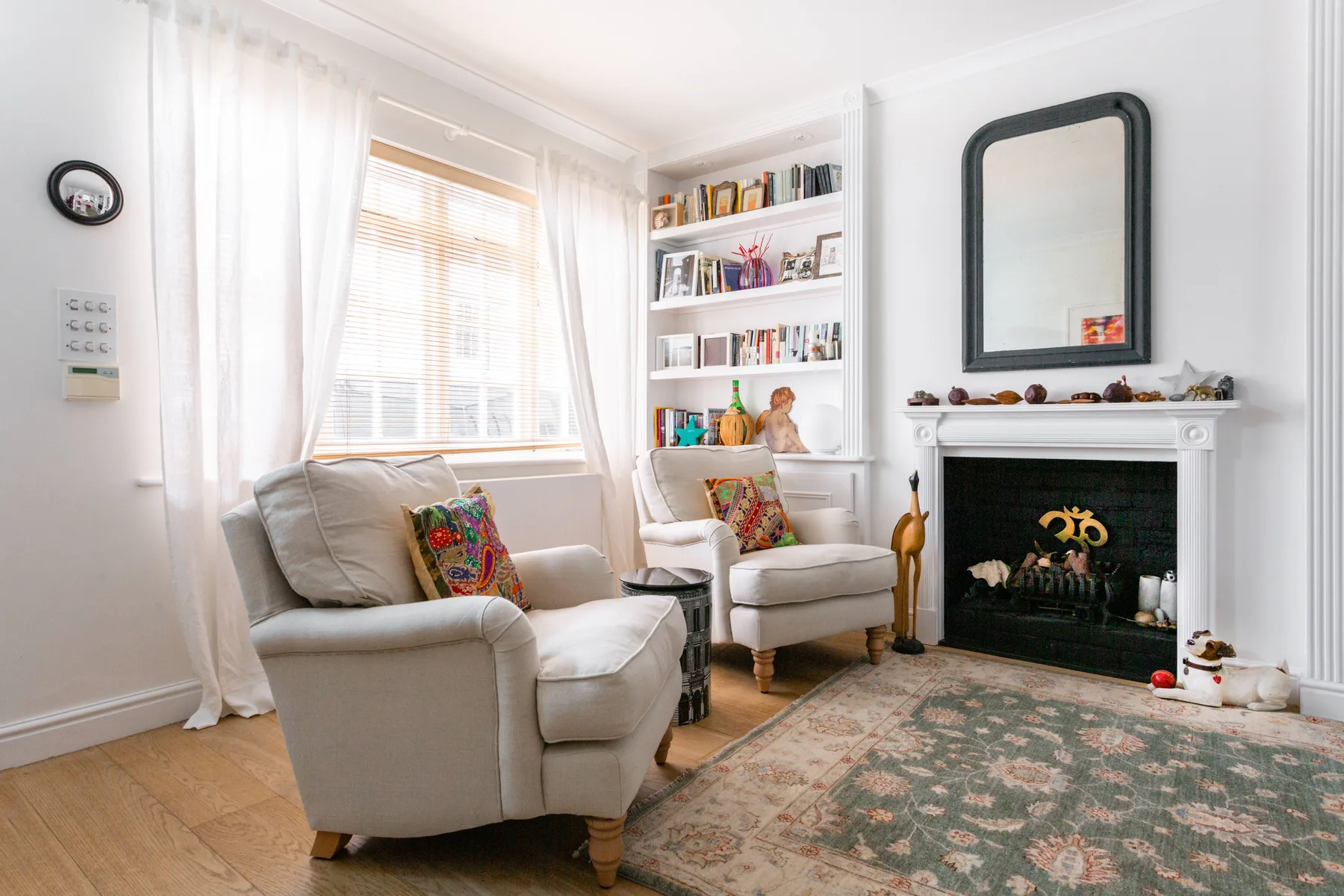Una sala luminosa con asientos junto a una chimenea y ventanas altas.