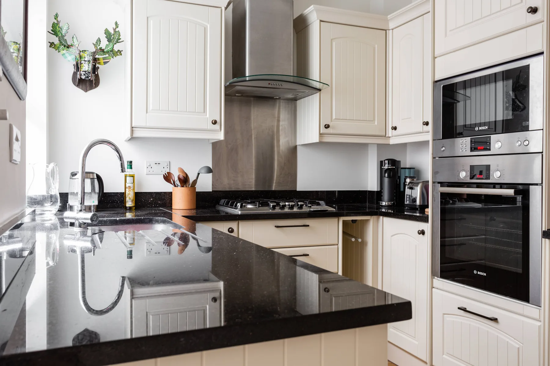 Una cocina luminosa con gabinetes claros, encimeras oscuras y electrodomésticos integrados.
