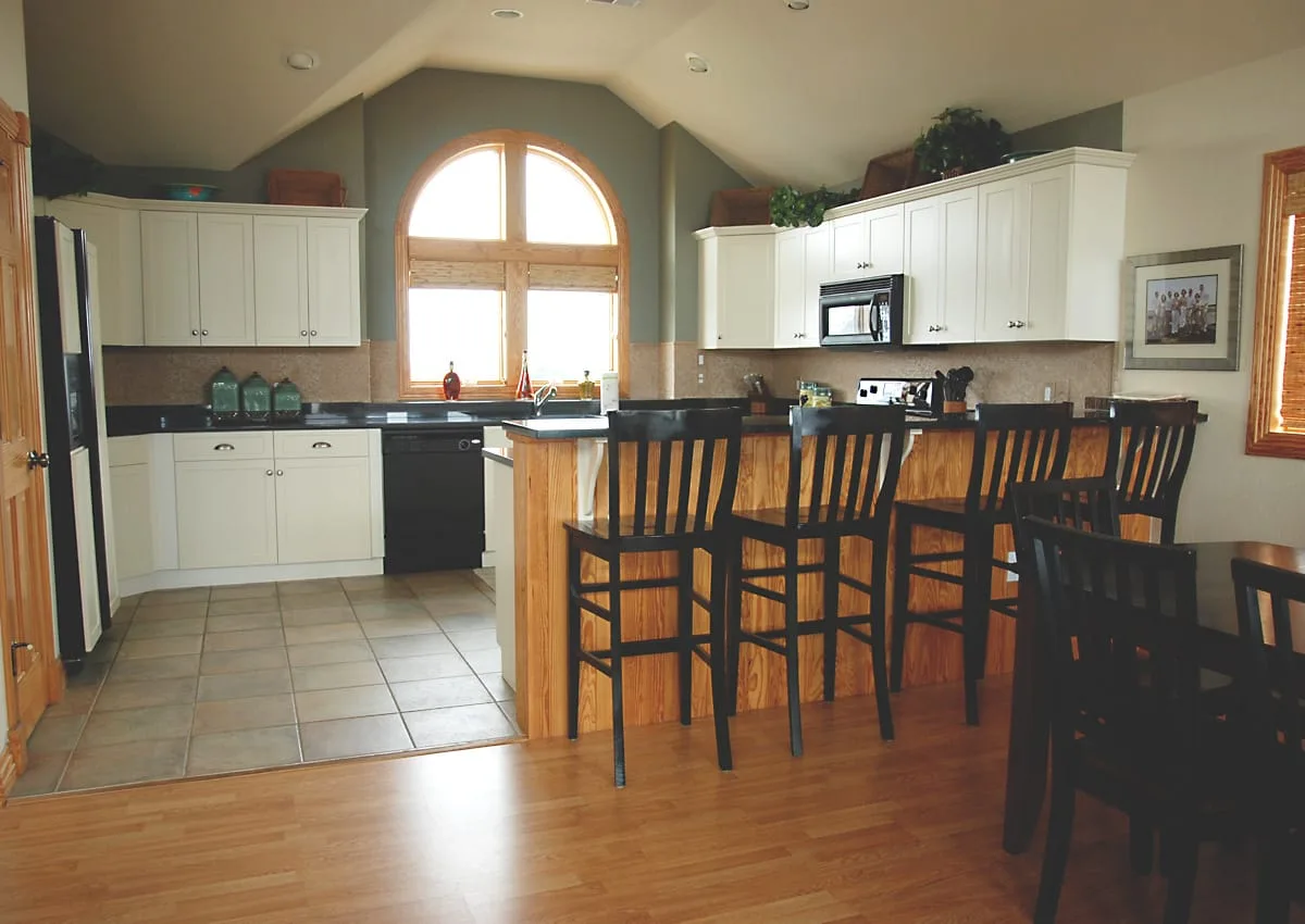Cocina y comedor con una barra y asientos altos.