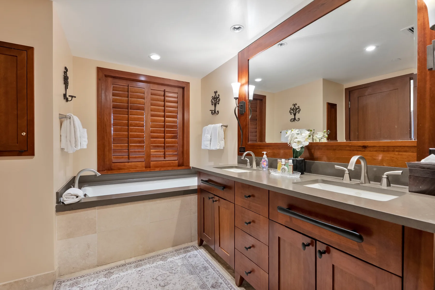 Un tocador de baño con un espejo grande, lavabos y gabinetes de madera.