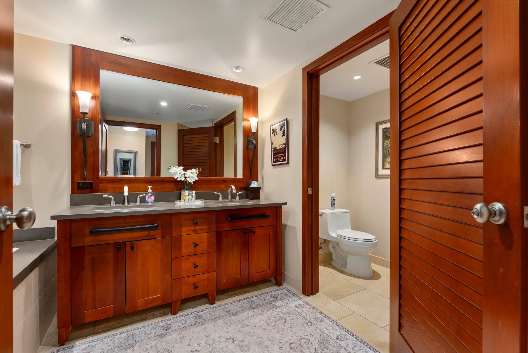 Un mueble de baño con un espejo grande junto a una puerta abierta que da al inodoro.