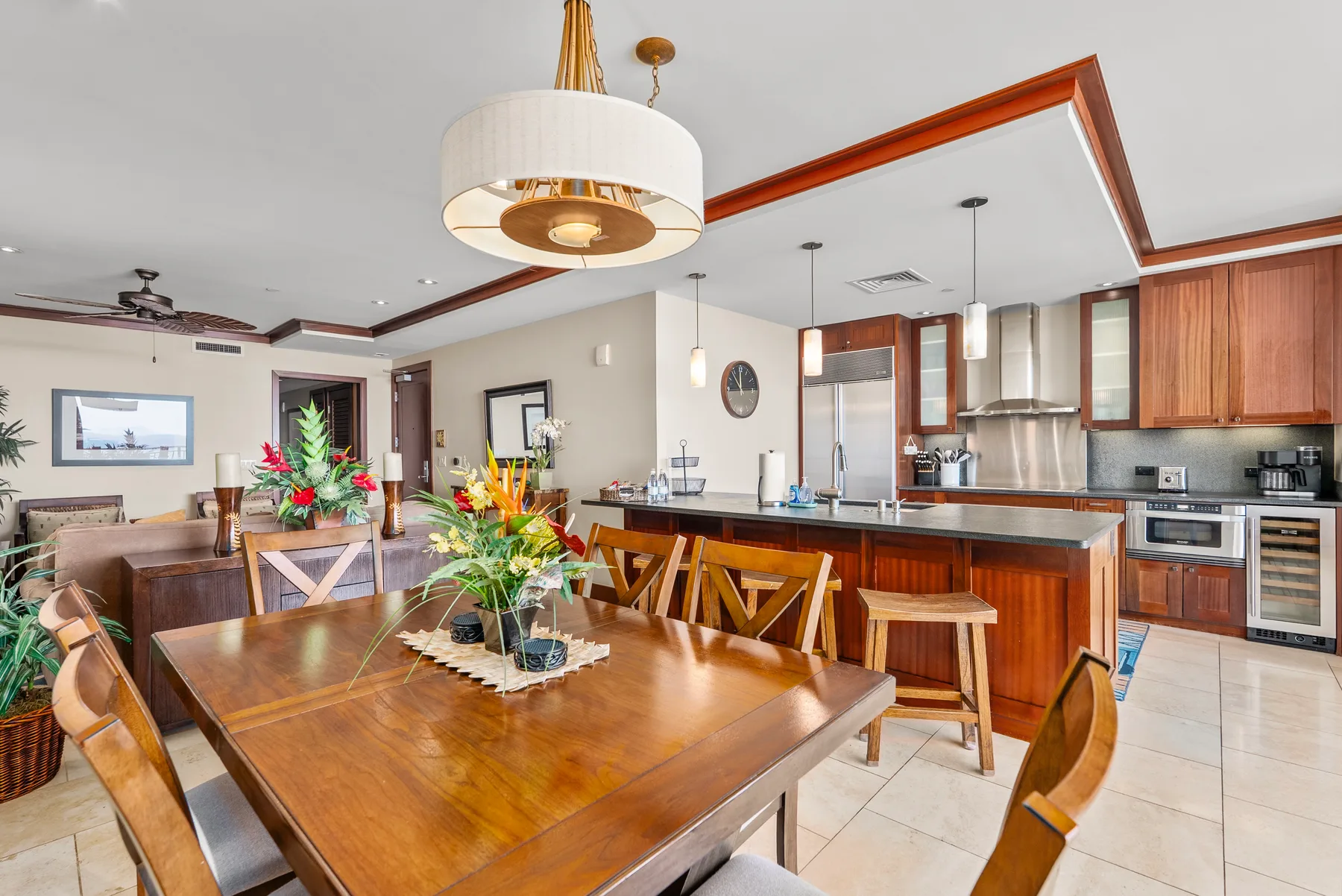 Un espacio abierto de comedor y cocina con una mesa de madera y asientos junto a la barra.