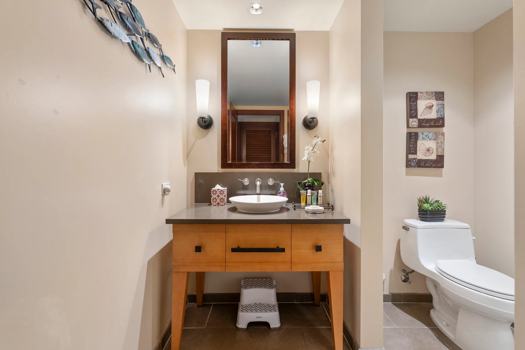 Un tocador de baño con lavabo y espejo está junto a un inodoro.