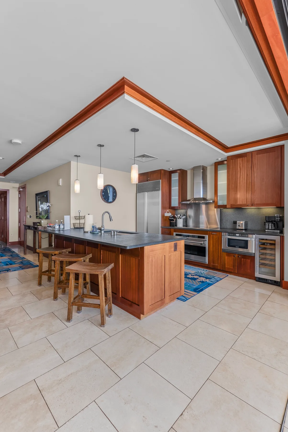 Una cocina con una isla central, gabinetes de madera y lámparas colgantes.